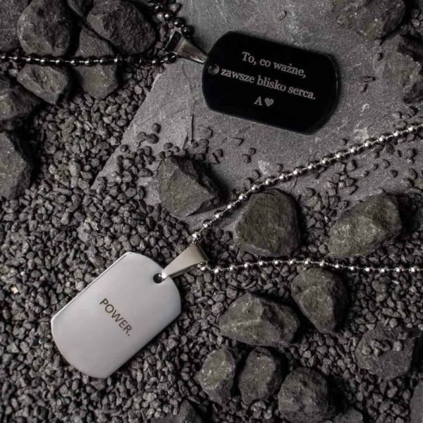 Dwa naszyjniki na tle ciemnych kamieni; jeden z napisem 'POWER', drugi z napisem 'To, co ważne, zawsze blisko serca. A♥'
