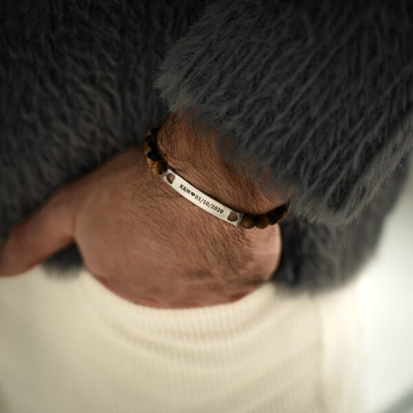 Osoba nosząca bransoletkę z wygrawerowaną datą i inicjałami.