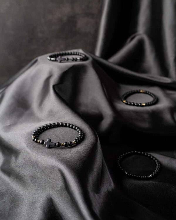 Czarne bransoletki z koralików na ciemnym tle z materiału.