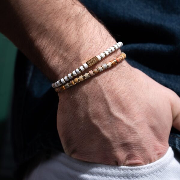 Męska ręka z dwoma bransoletkami z koralików.