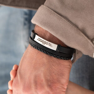 Męska ręka w bransoletce z napisem, trzymająca dłoń dziecka.